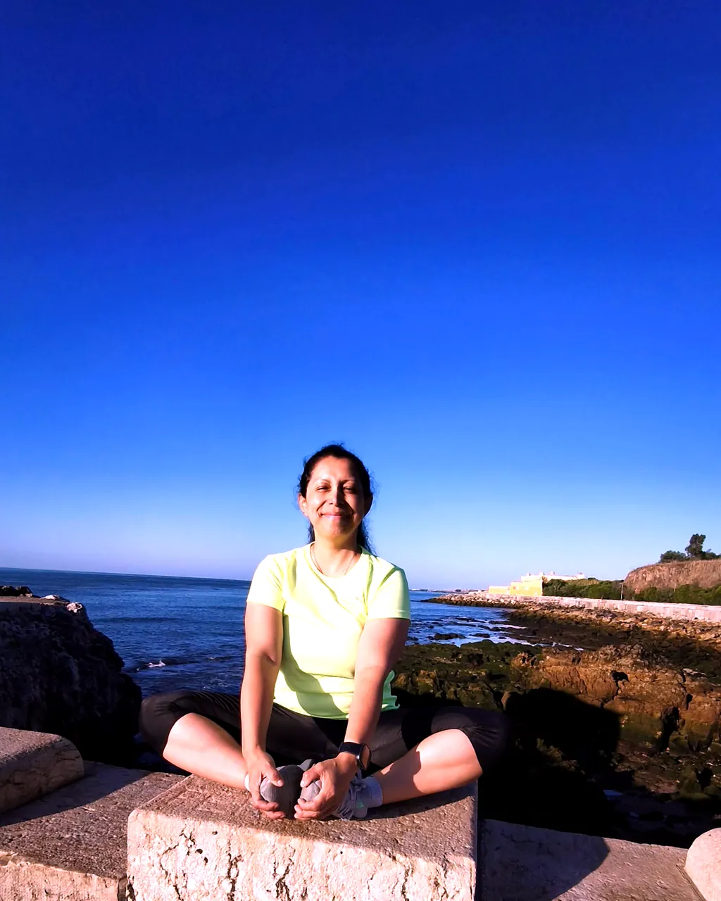Liliana Martins sentada a sorrir, junto ao mar