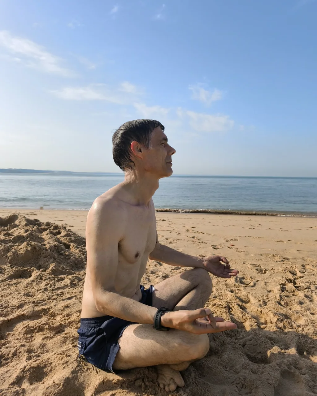 Paulo Martins de perfil, sentado em concentração na areia